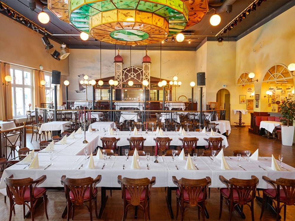 Großzügiger Festsaal Belle Époque von Schöner Inseln mit festlich gedeckten Tafeln und farbenprächtiger Deckenleuchte auf Usedom.