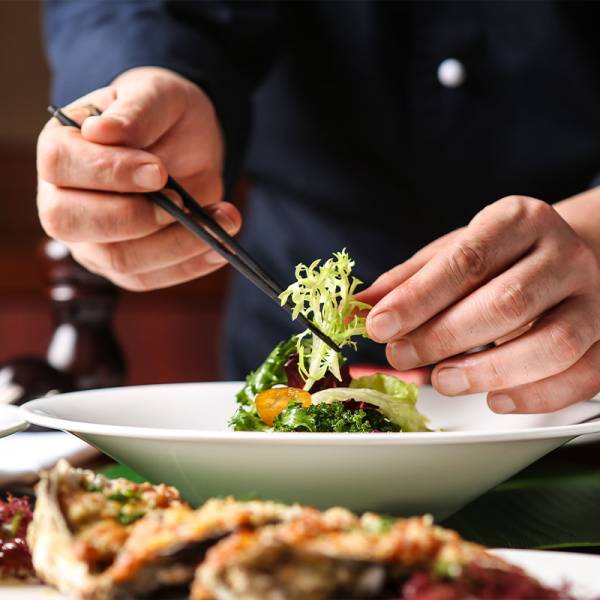 Nahaufnahme vom Anrichten eines eleganten Gerichts mit Salat, Zitrone und Meeresfrüchten im Restaurant auf Usedom.