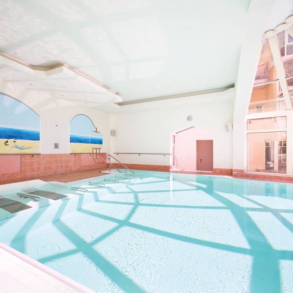 Moderner Indoorpool mit großer Fensterfront, Tageslicht und Strandmotiven an den Wänden im Preussen-Vital-Spa auf Usedom.