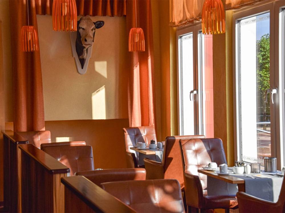 Blick in den sonnendurchfluteten Gastraum des Alex Steakhouse auf Usedom mit gedeckten Tischen und rustikalem Ambiente.