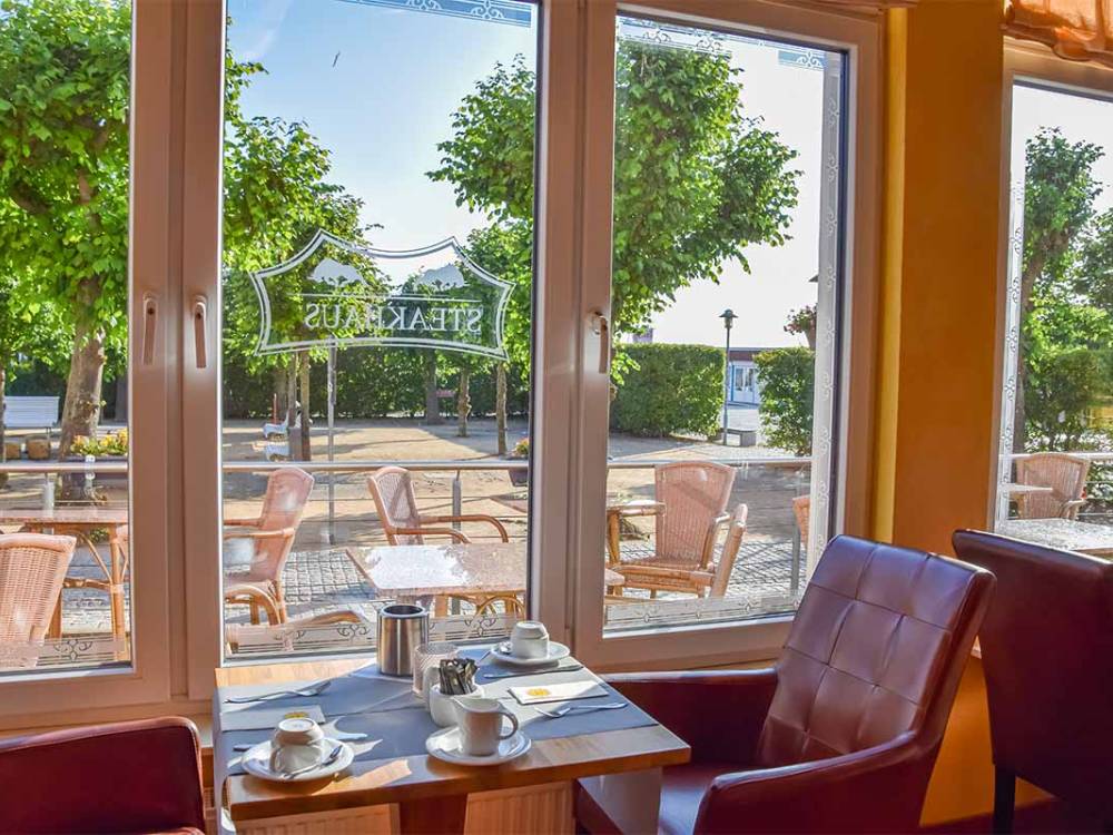 Ausblick vom gedeckten Tisch im Alex Steakhouse auf Usedom mit Sicht auf die Terrasse und Bäume der Promenade Zinnowitz.