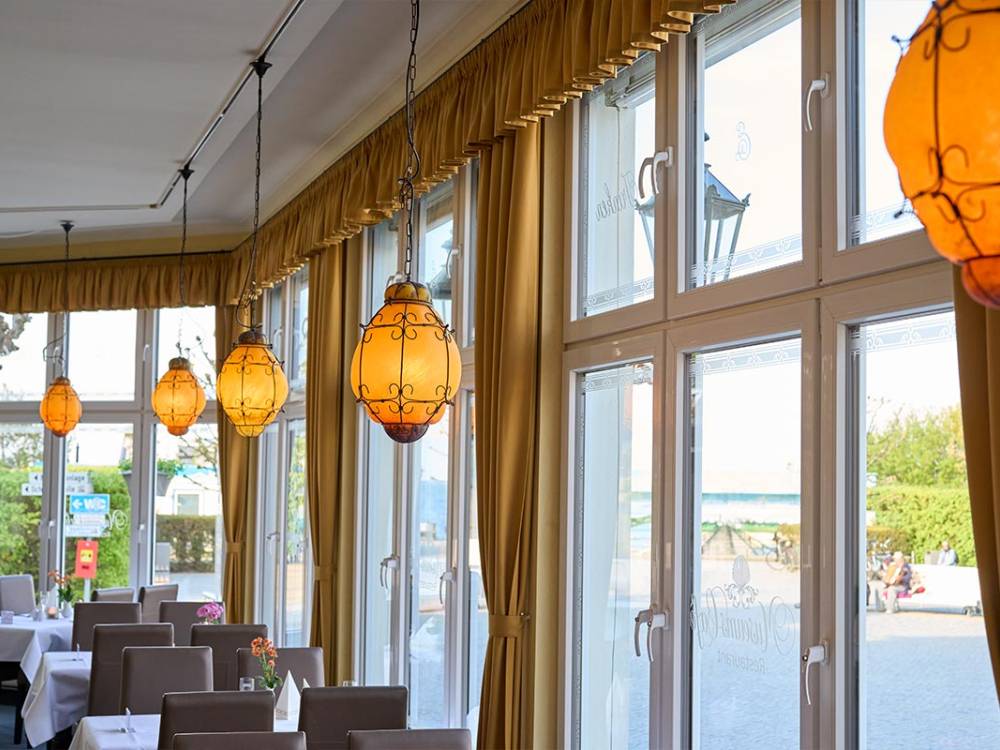 Blick aus dem Restaurant Lineti von Schöner Inseln mit gedeckten Tischen und großen Fenstern und Meerblick auf Usedom.