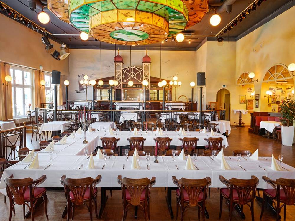 Großzügiger Festsaal Belle Époque von Schöner Inseln mit festlich gedeckten Tafeln und farbenprächtiger Deckenleuchte auf Usedom.