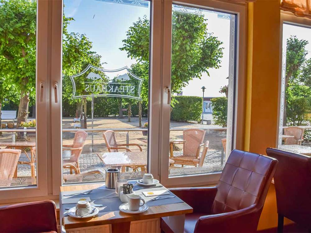 Ausblick vom gedeckten Tisch im Alex Steakhouse auf Usedom mit Sicht auf die Terrasse und Bäume der Promenade Zinnowitz.