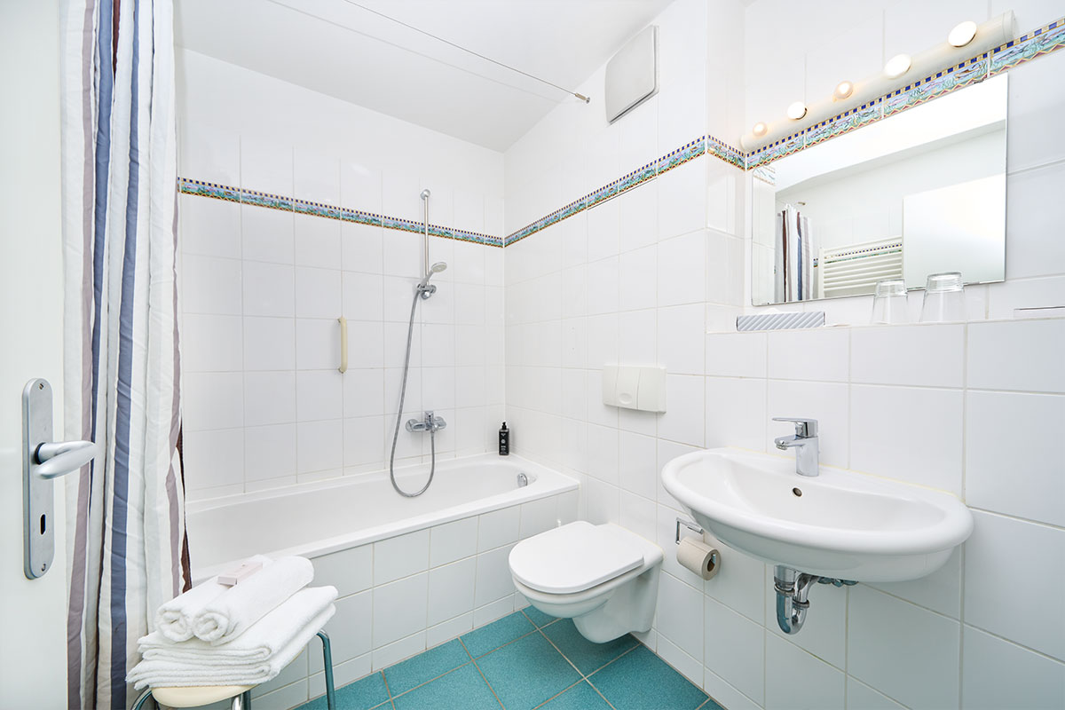 Ausstattung des 1-Raum-Apartments in Zinnowitz mit moderner Einrichtung, frischen Handtüchern und weißen Fliesen.