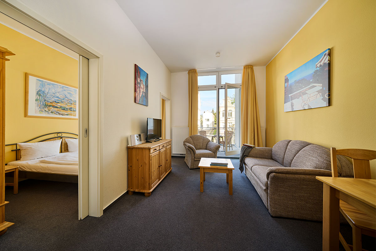 Gemütlicher Wohnbereich mit Sofa, TV und Balkonzugang in den Ferienwohnungen der Strandperle auf Usedom.