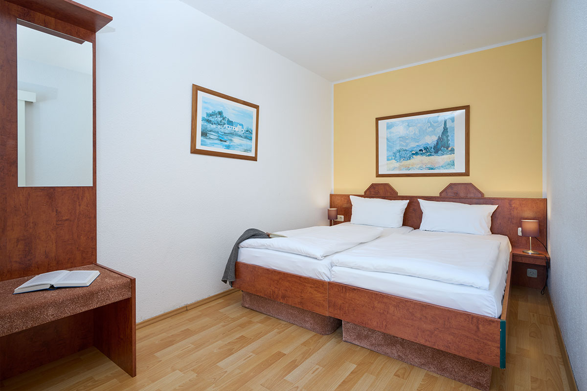 Gemütliches Schlafzimmer mit Doppelbett und warmen Farben in den Ferienwohnungen der Schöner Inseln auf Usedom.