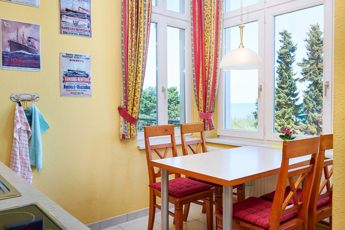 Essbereich mit vier Stühlen, gelben Wänden und Meerblick in einer Ferienwohnung auf Usedom.