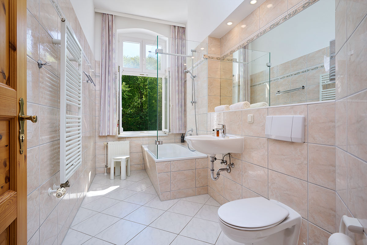 Grosses Badezimmer mit Badewanne, WC und Fenster in einer stilvollen Ferienwohnung in Zinnowitz auf der Ostseeinsel Usedom.