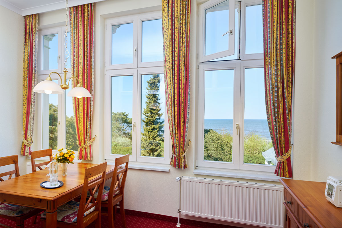 Essbereich mit Holztisch und Panoramablick auf die Ostsee in einer Ferienwohnung in Zinnowitz auf Usedom.