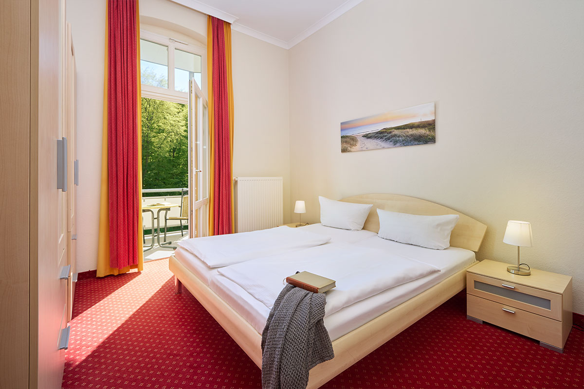 Schlafzimmer mit Doppelbett und Balkonzugang in einer Ferienwohnung der Strandvillen Wald und See auf Usedom.