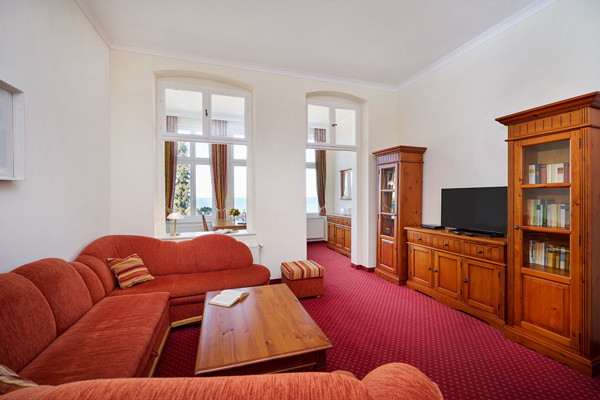 Wohnbereich mit Ecksofa, TV und Meerblick in einer stilvollen Ferienwohnung der Strandvillen Wald und See auf Usedom.