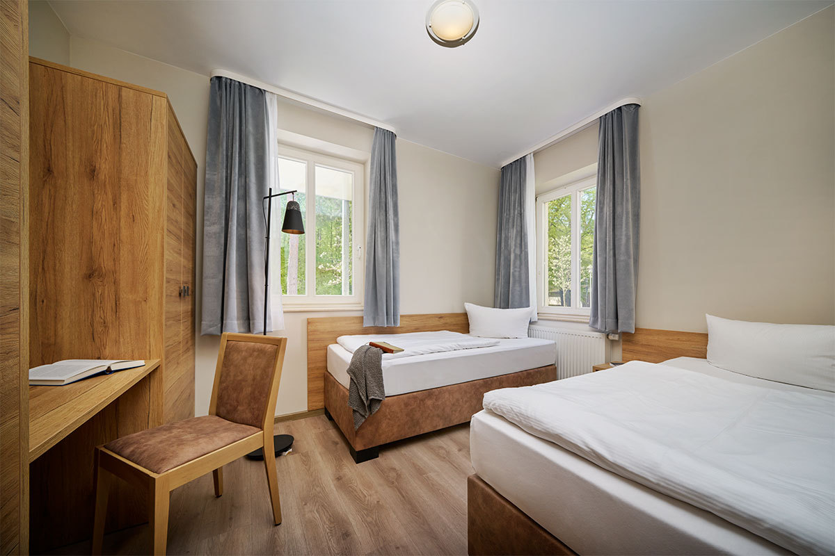 Schlafzimmer mit Doppelbett, Einzelbett und Schreibtisch in einer Familiensuite der Ostseeinsel Usedom.