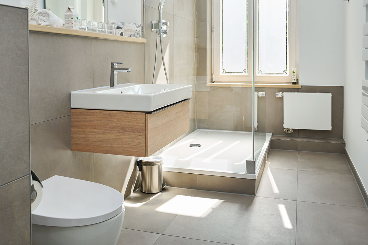 Modernes Bad mit ebenerdiger Dusche, WC und Fenster in der Familiensuite zur Meerseite auf Usedom.