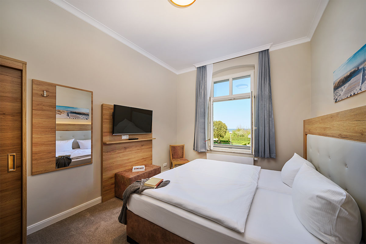 Schlafzimmer mit Doppelbett, Fenster und TV in der Familiensuite zur Meerseite an der Ostsee.