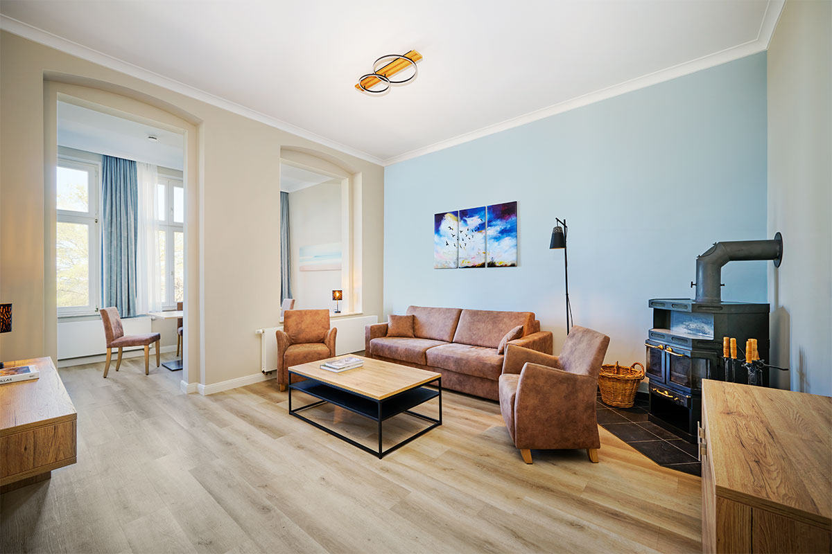 Wohnbereich mit Sofa, Sessel und hellem Holzfussboden in der Familiensuite zur Meerseite auf Usedom.