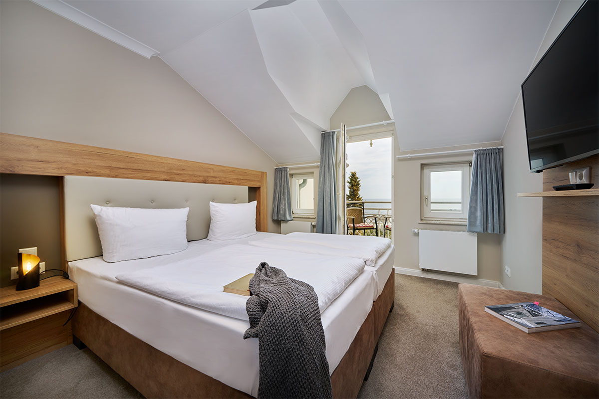 Schlafzimmer mit Doppelbett, TV und Balkonzugang mit Ostseeblick in der Juniorsuite auf Usedom.