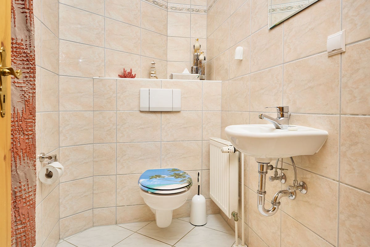 Modernes WC mit Handwaschbecken und Fliesen in der Juniorsuite zur Landseite auf Usedom.