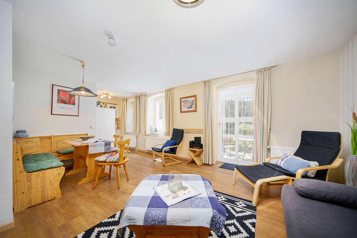 Wohnbereich mit Sitzecke, Esstisch und viel Tageslicht in der Juniorsuite an der Ostsee.