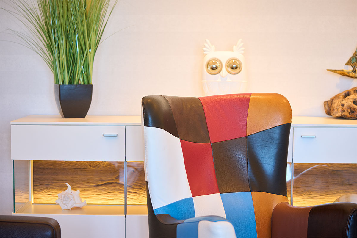 Bunter Designersessel vor Sideboard mit Dekoration in der Ostsee Deluxe Suite in Zinnowitz.