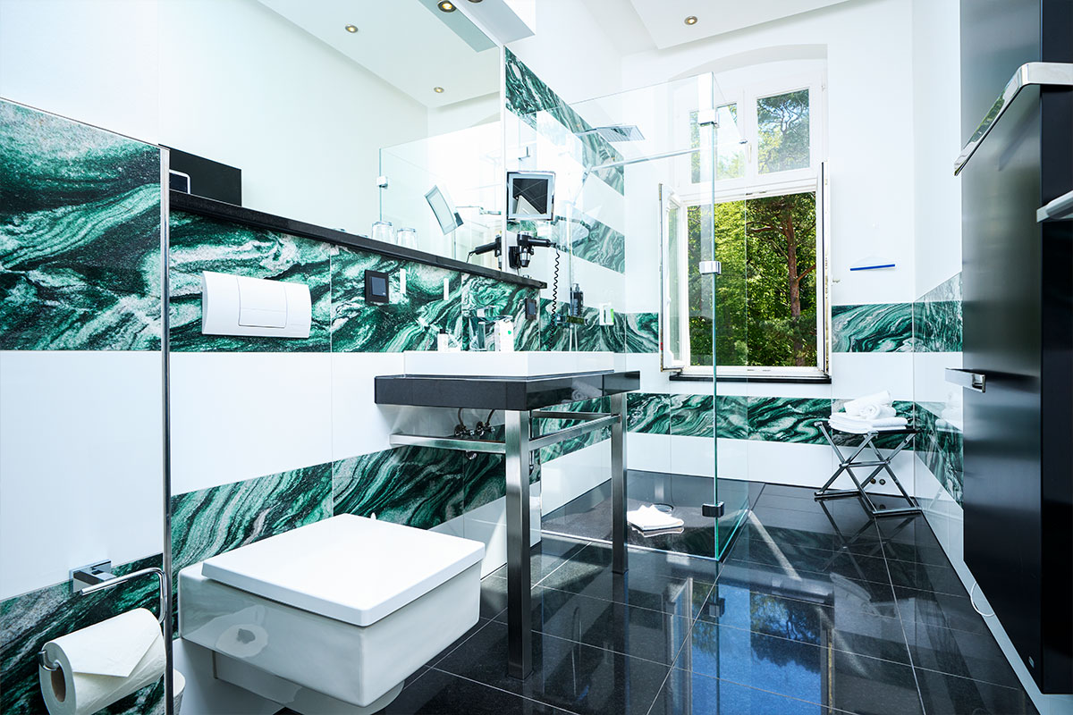 Modernes Bad mit grün-weissen Marmorfliesen, Dusche und großem Spiegel in der Ostsee Deluxe Suite.