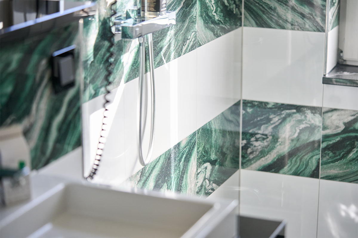Dusche mit grün-weiss gemusterten Fliesen und moderner Ausstattung in der Ostsee Deluxe Suite in Zinnowitz.