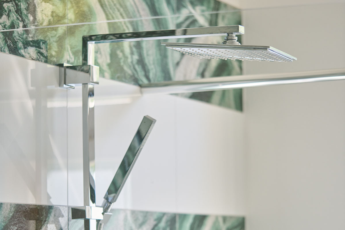 Moderne Regendusche mit grün gemusterter Wandverkleidung in der Ostsee Deluxe Suite in Zinnowitz.