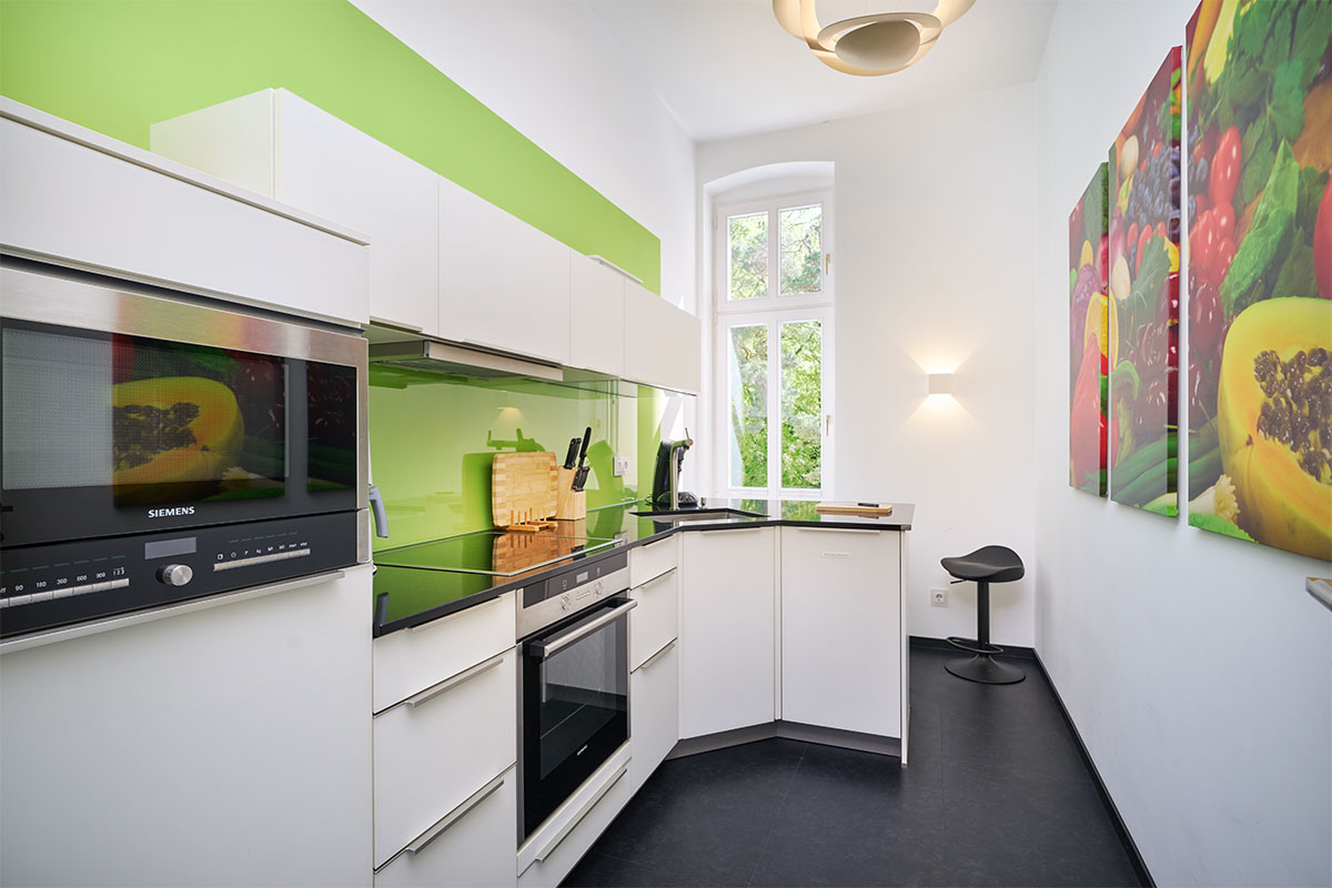 Moderne Einbauküche mit grüner Wand und hellen Möbeln in der Ostsee Deluxe Suite auf Usedom.