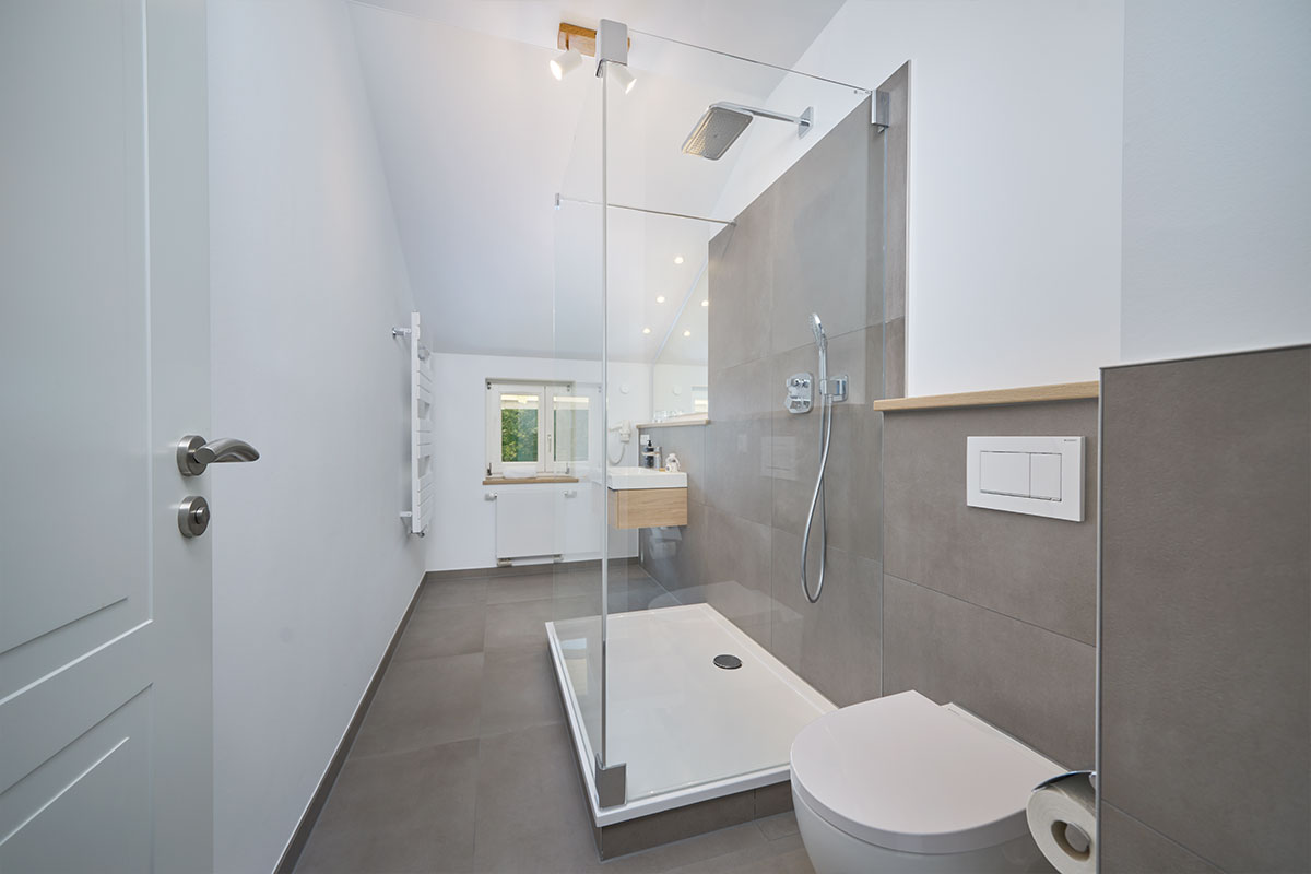 Helles Bad mit begehbarer Dusche und WC in einer Suite mit Panorama-Meerblick auf Usedom.