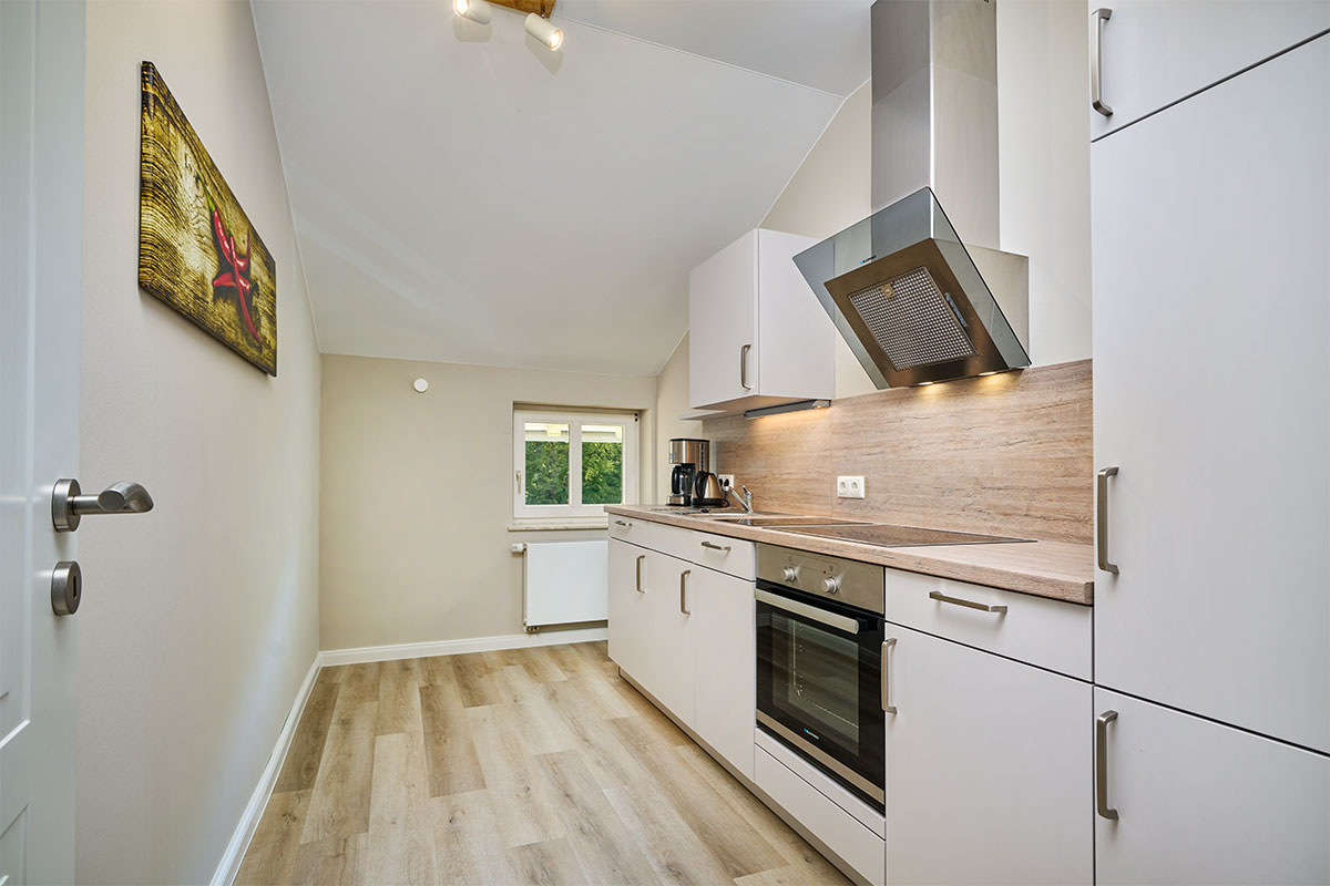 Helle Einbauküche mit Holzdetails in der Suite mit Panorama-Meerblick auf Usedom.