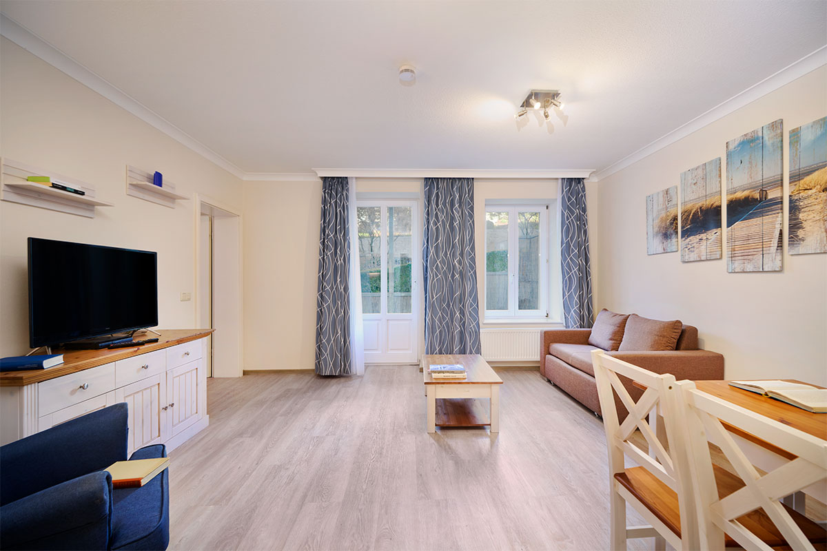 Heller Wohnbereich mit gemütlicher Sitzecke und Esstisch in der Ferienwohnung Zinnowitzer Hof auf Usedom.