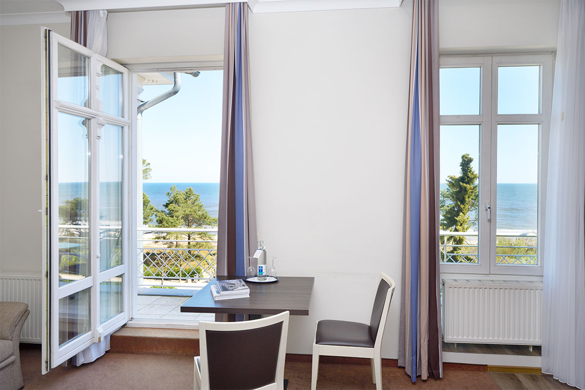 Tisch mit zwei Stühlen am Fenster mit direktem Blick auf die Ostsee im Studio Apartment des Strandpalais in Zinnowitz.