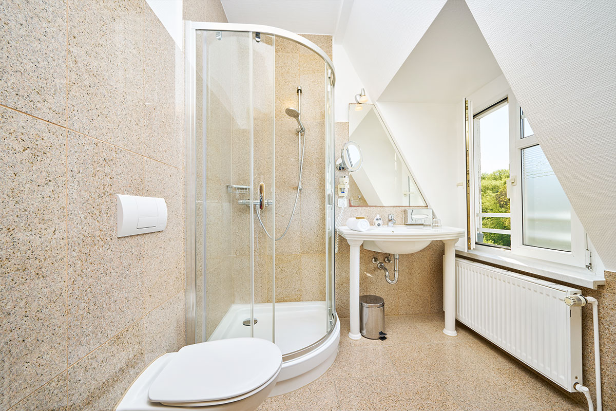 Helles Badezimmer mit Dusche und Fenster im Strandhotel Garni Kormoran an der Ostsee.