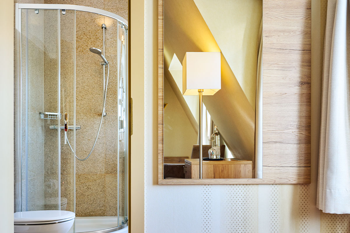 Detailansicht mit Dusche und Spiegel im modernen Zimmer des Strandhotels Garni Kormoran.