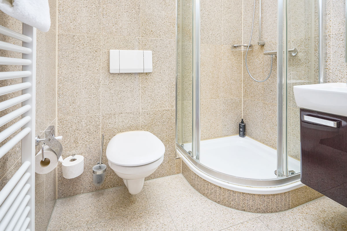 Badezimmer im Einzelzimmer des Strandhotels Kormoran mit Dusche, WC, Waschbecken und Handtuchhalter.