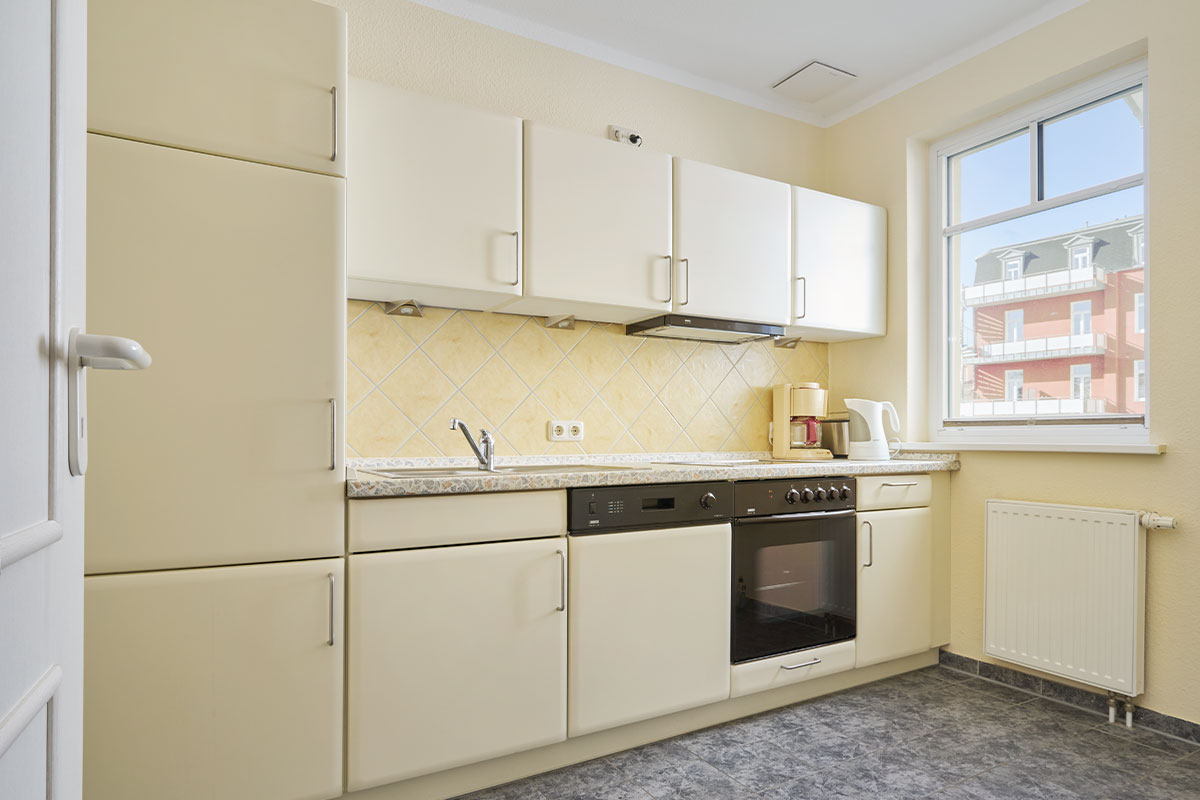 Küche mit Backofen, Ceranfeld, Spüle und Kaffeemaschine im Economy Apartment des Strandhotel Luise auf Usedom.