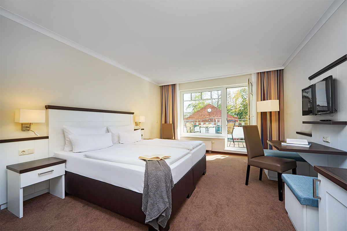 Economy Doppelzimmer im Strandhotel Luise mit Bett, Schreibtisch, Sessel, TV und Fenster zur Landseite.