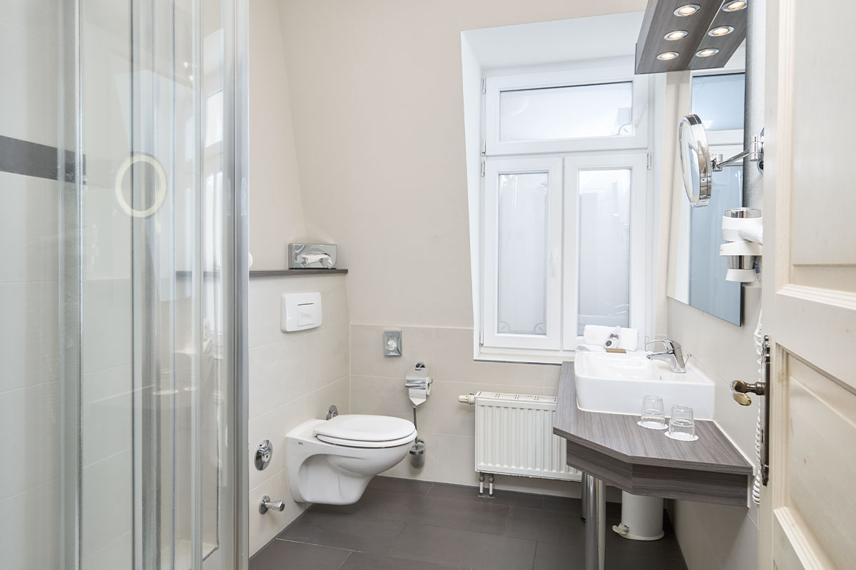 Modernes Bad im Doppelzimmer des Strandhotel Preußenhof mit Dusche, WC, Fenster und Waschtisch.