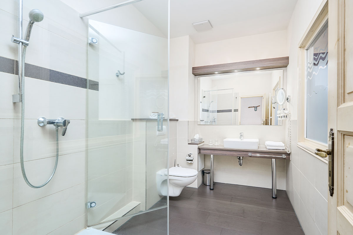 Helles Badezimmer im Strandhotel Preußenhof auf Usedom mit Dusche, WC, Waschtisch und Spiegel.