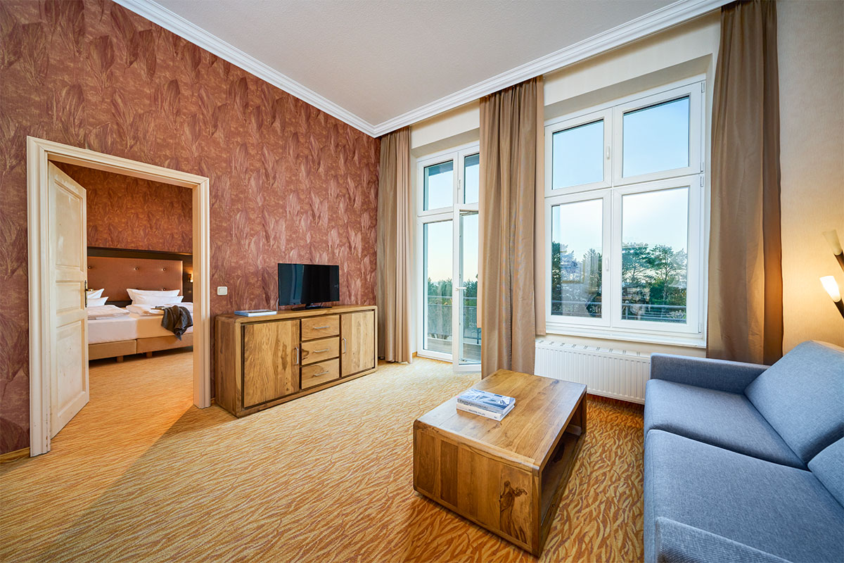 Wohnbereich der Family Suite im Strandhotel Preußenhof auf Usedom mit Sofa, TV und Balkon zur Ostsee.