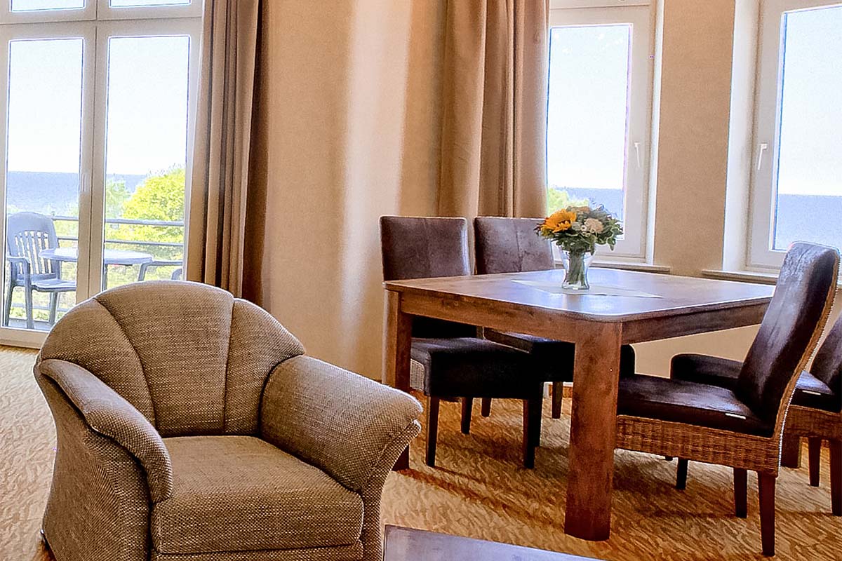 Wohnbereich mit Sessel, Esstisch und Meerblick in der Familiensuite im Strandhotel Preussenhof auf Usedom
