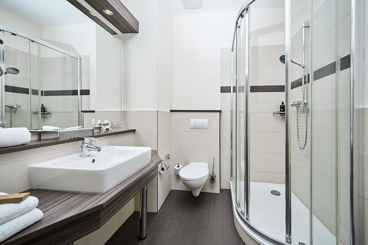 Modernes Bad der Juniorsuite im Strandhotel Preußenhof mit Dusche, WC, Waschbecken und Spiegel.