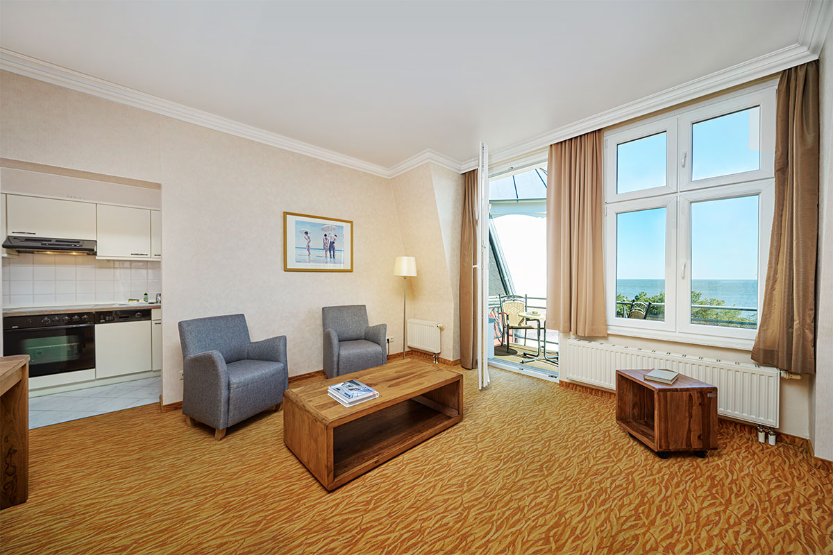 Wohnbereich der Juniorsuite im Strandhotel Preußenhof mit Meerblick, Sesseln, Tisch und Balkon.