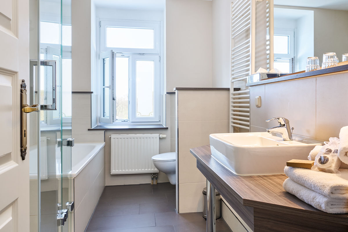 Modernes Bad mit Fenster, Dusche, Waschbecken und Handtüchern im Strandhotel Preußenhof.