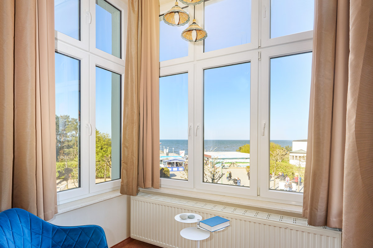 Ausblick aus der Turm Suite im Strandhotel Preußenhof auf Promenade und Ostsee mit Fenstern.