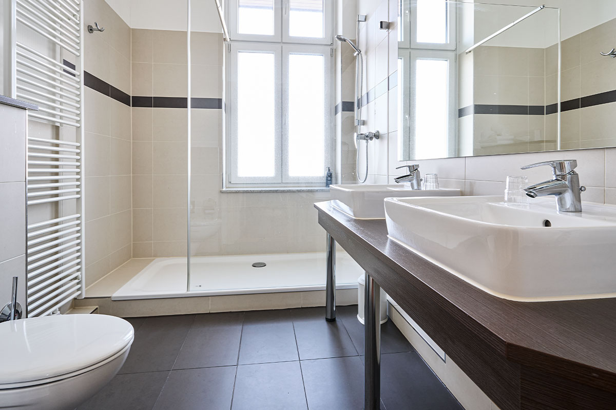 Modernes Bad in der Turm Suite im Strandhotel Preußenhof mit Dusche, Doppelwaschbecken und Fenster.
