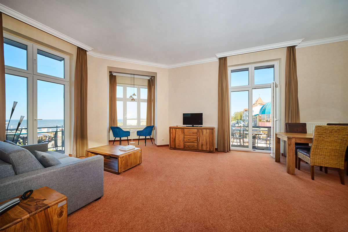Wohnzimmer der Turm Suite im Strandhotel Preußenhof mit Sofa, TV, Essbereich und Meerblick.