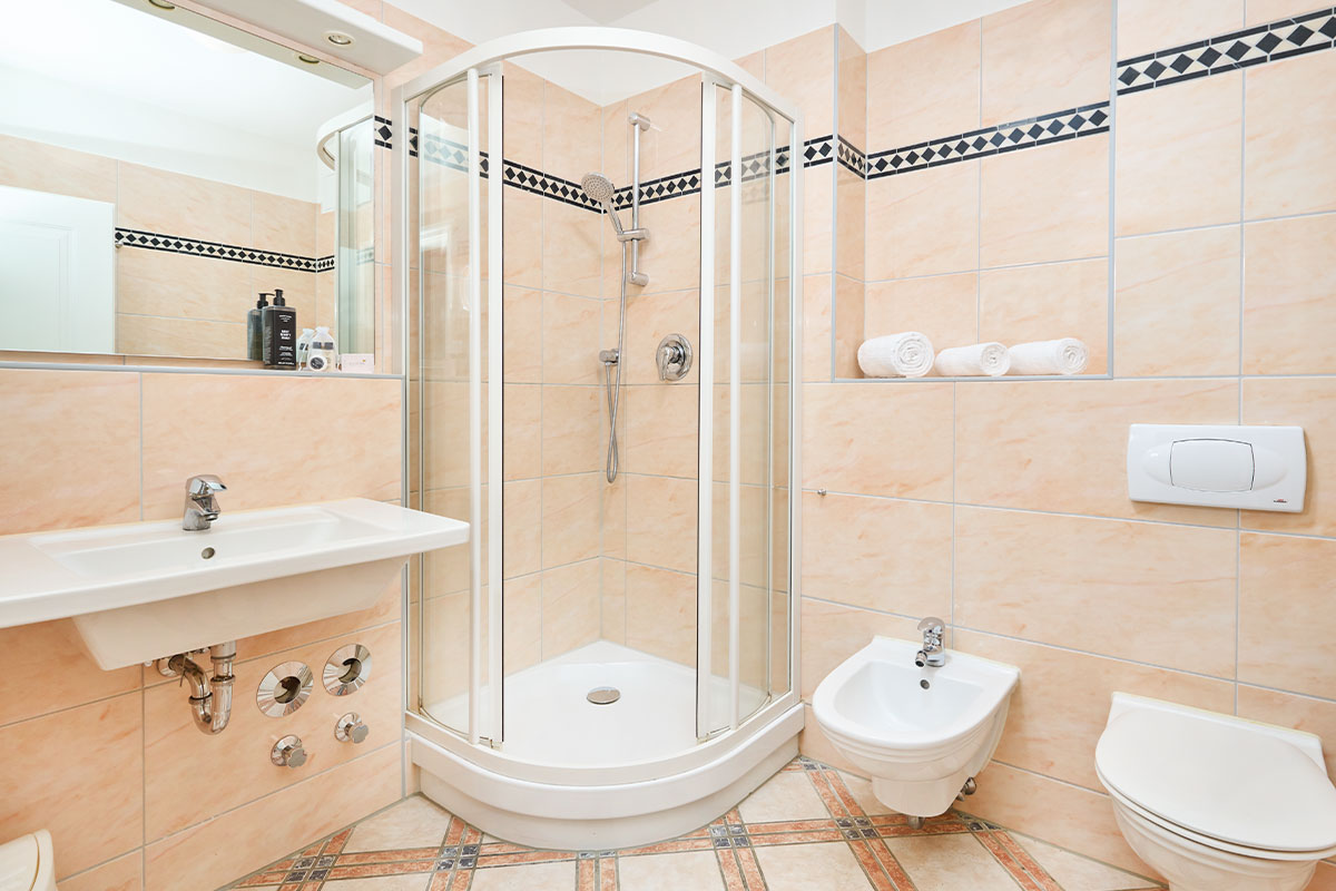 Modernes Badezimmer im Strandhotel Prinz von Preussen auf Usedom mit Dusche, Keramikwaschtisch, Bidet und gefliester Wand.
