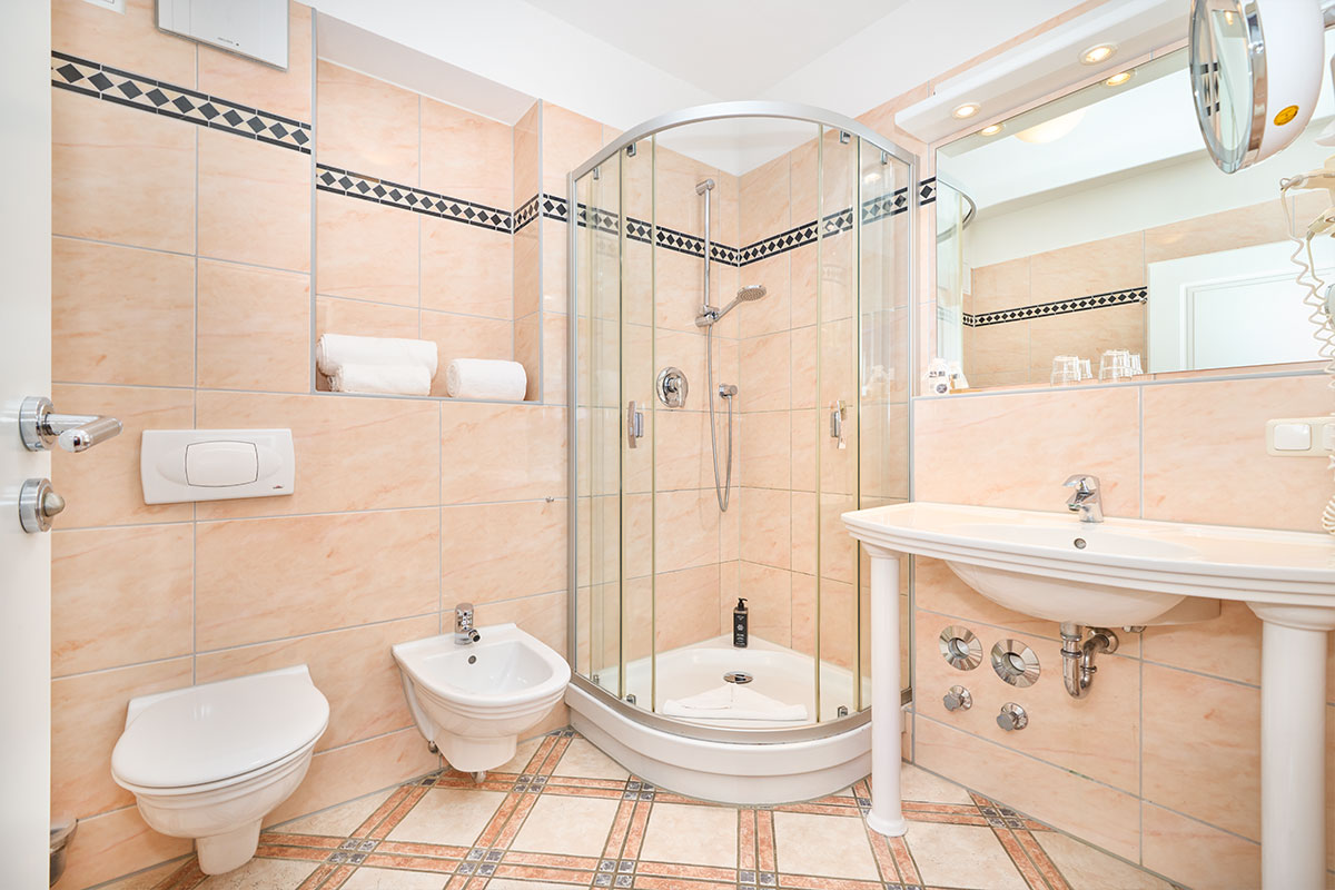 Modernes Hotelbad mit Glasdusche, Bidet, WC, Waschbecken und Spiegel im Strandhotel Prinz von Preussen.