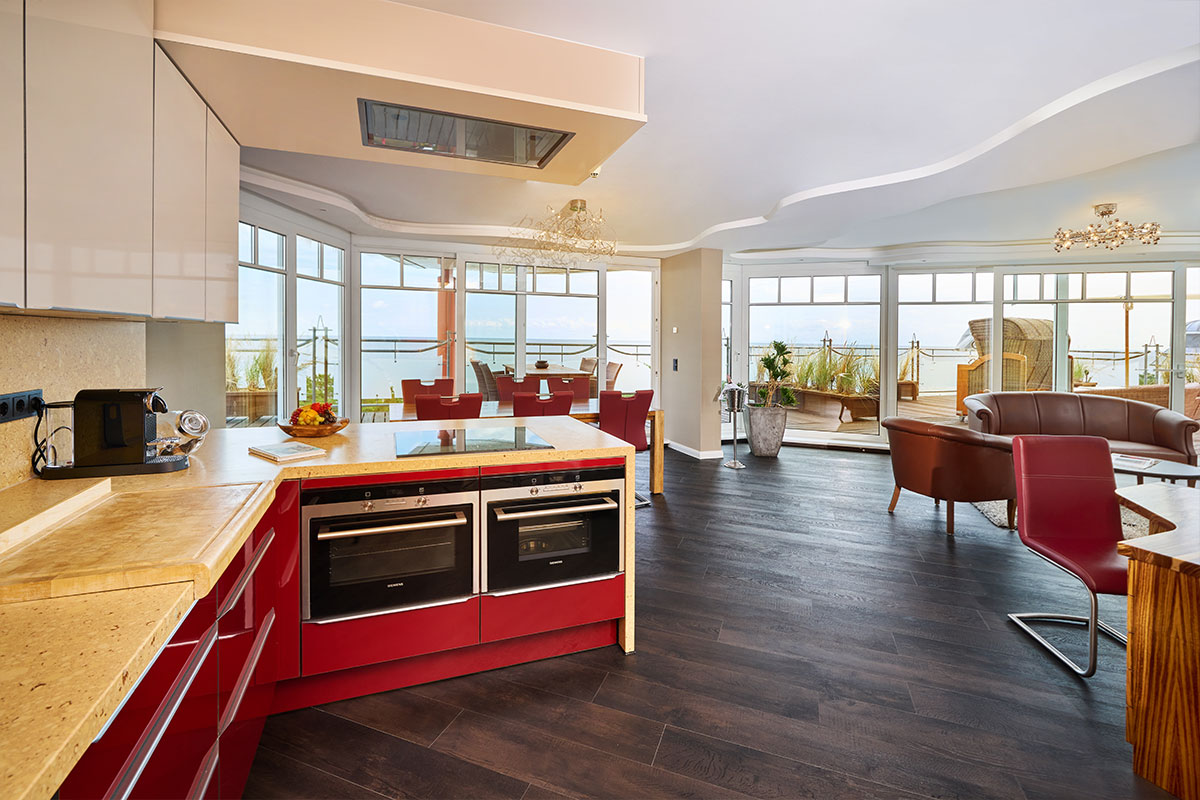 Moderne, offene Designküche im Strandhotel Prinz von Preussen mit roten Fronten, großem Wohnraum und Ostseepanorama.